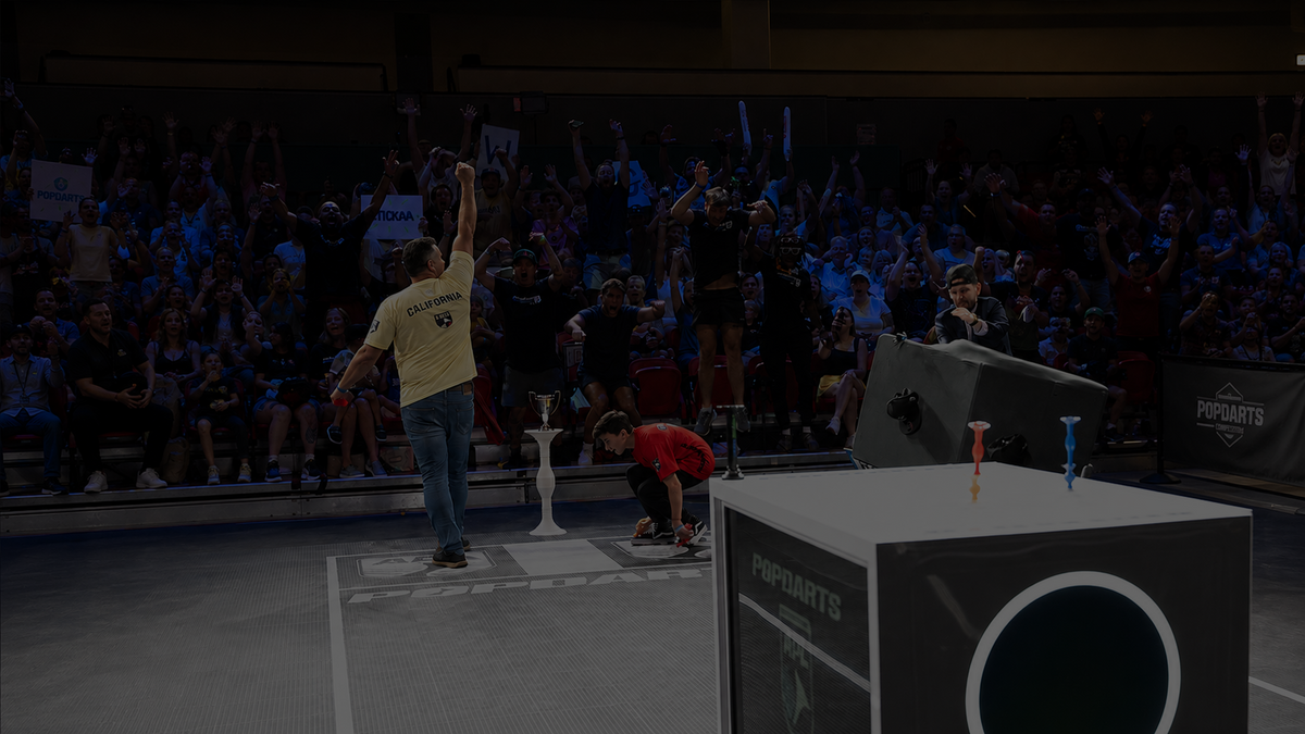 A champion lifted on shoulders holding the Popdarts National Championship trophy.